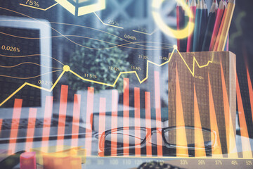 Financial chart hologram with glasses on the table background. Concept of business. Double exposure.