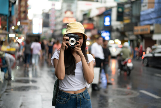 Asian traveler girl with instant camera   take a photo on the street in China town Thailand.