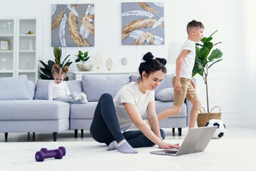 Happy mom on the floor at home with kids and watch funny cartoon on laptop.