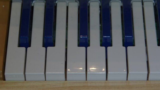 Games for children inside the house. The keys of a small piano filmed from the camera in slow motion.