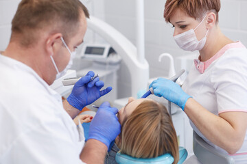 Obraz premium Doctor dentist treats teeth of a beautiful young girl patient. The girl on reception at the dentist. Doctor dentist treats tooth