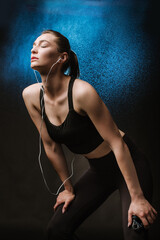 Obraz premium Slim fitness woman in black sport suit posing on black background