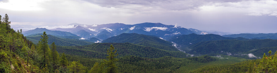 Sayan mountains view after rain. Low clouds and rain clouds. Panorama
