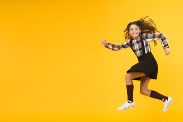 Fototapeta na wymiar Happy childrens day. Jump concept. Break into. Feel inner energy. Girl with long hair jumping on yellow background. Carefree kid summer holiday. Time for fun. Active girl feel freedom. Fun and jump