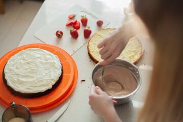 A young woman interferes with cream for a cake's bowl. Cooking holiday cake. Cooking Cake Cream