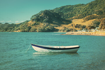 Fototapeta na wymiar Retro-style photo of a wooden row boat moored in calm waters of the bay