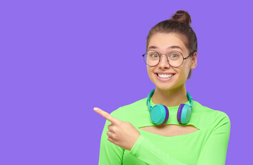 Excited teen girl in green top and glasses, pointing left to copy space, feeling , isolated on...