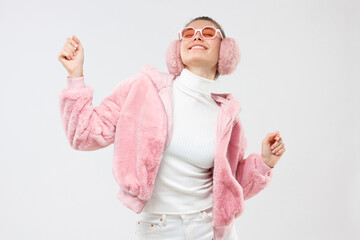 Young female in pink funky outfit, moving arms, smiling and dancing to sounds of music at party, enjoying her free time, isolated on gray background