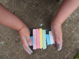 Educational games in the open air. Pieces of chalk pastel colors in children's hands. Top wiew.