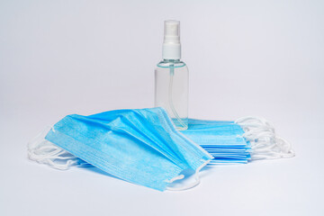 bottle of lotion, sanitizer or liquid soap and protective mask over light grey background