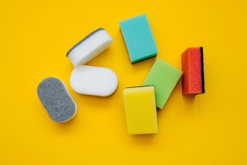 Bunch of white and colorful dish sponges on bright yellow background. Concept of cleaning.