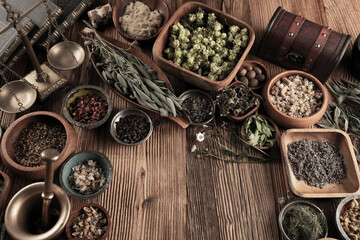Large spice and herb collection in bowls and spoons forming an abstract background.