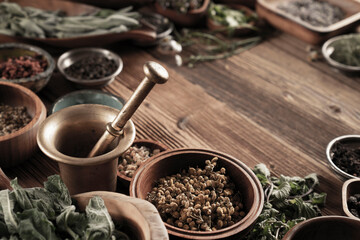 Large spice and herb collection in bowls and spoons forming an abstract background.
