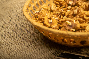 Peeled walnuts in a wicker basket on a wooden table covered with rough-textured burlap. Healthy diet. Fitness diet. Close up.