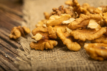 Peeled walnuts in bulk on a wooden table covered with rough-textured burlap. Healthy diet. Fitness diet. Close up.