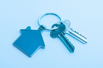 key chain with house symbol and keys on blue background,Real estate concept
