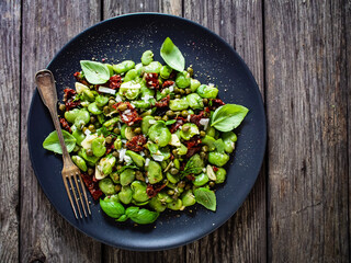 Broad beans salad with sun dried tomatoes, garlic and onion on wooden table
