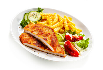 Breaded fried pork chop, French fries and vegetables on white background
