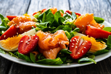 Salmon salad - smoked salmon boiled egg and vegetables on wooden background
