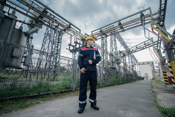 An electrical substation engineer inspects modern high-voltage equipment in a protective mask ....
