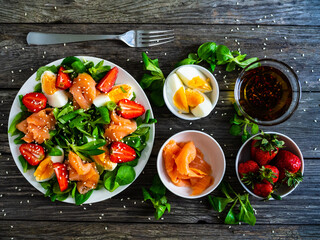 Salmon salad - smoked salmon boiled egg and vegetables on wooden background
