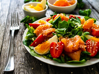 Salmon salad - smoked salmon boiled egg and vegetables on wooden background
