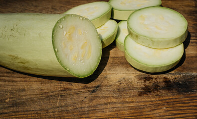 Fresh zucchini and slices of zucchinis on wooden table. Sliced courgette, healthy vegan diet or vegetarian food, cooking concept.