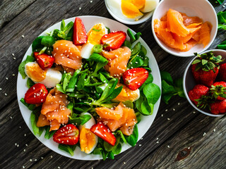 Salmon salad - smoked salmon boiled egg and vegetables on wooden background
