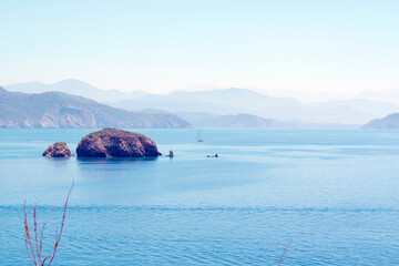 Yachting concept seascape, blue sea, mountains, sky, small island and sailing boat