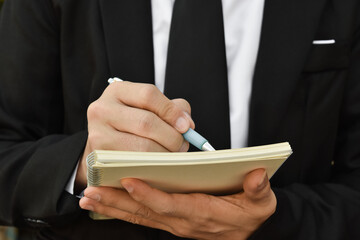 Close-up of businessman hand writing a note at business document, signing contract, partnership agreement.