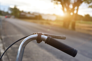 Close up of bicycle handle with sunset background.