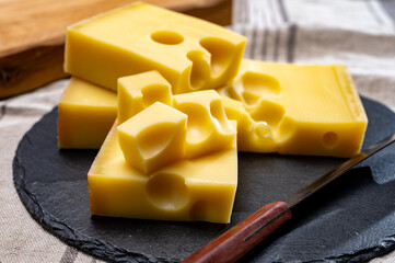 Block of Swiss medium-hard yellow cheese emmental or emmentaler with round holes and cheese knife