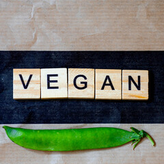 The word "vegan" written with vegetables on a wooden background