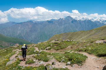 Fototapeta na wymiar Hiker on Mountain range on a hiking trail from Gergeti Trinity Church to Gergeti Glacier. a famous landscape in Kazbegi, Mtskheta-Mtianeti, Georgia.