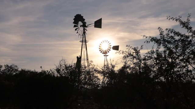 Rancher climbing a windmill on his farm looking at the sunset in the Karoo of South Africa.