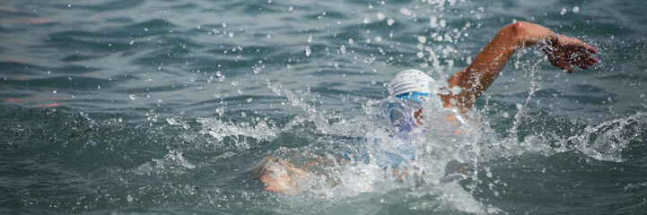 Swim triathlete man swimming freestyle crawl in ocean, panorama banner