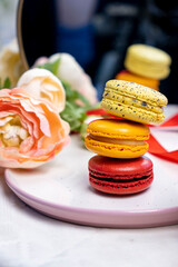 stack of colorful modern cakes cookies macaroons on plate  for celebration romantic party birthday, pion flowers, satin ribbon top view, many different types flavors of macarons dessert 