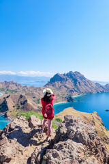 Fototapeta premium June 14, 2018 - Labuan Bajo, Komodo National Park, Indonesia : Asian girl in red cardigan taking a shot/picture on top of Padar Island.