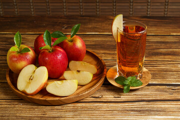 Apple juice and a red apple on a wooden table.