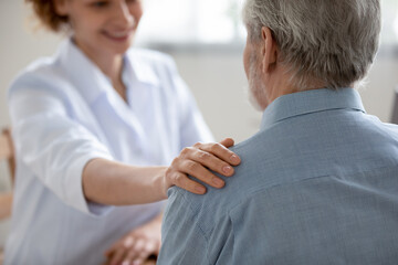 Close up of caring woman doctor or GP touch comfort caress senior male patient at consultation in hospital, smiling female nurse or caregiver support upset mature man, elderly healthcare concept