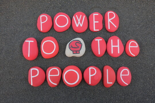 Power to the people, protest slogan composed with red colored stones over black volcanic sand