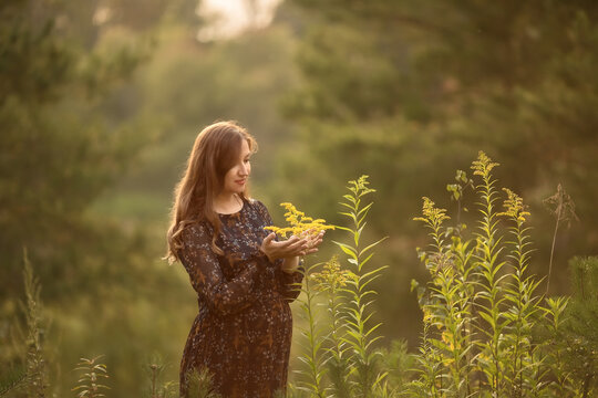 A pregnant young woman is standing on the Bank of the river. Image with selective focus.