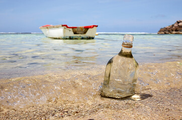 Seychelles landscape waterscape from Mahe Indian ocean loan boat red trim turquoise water golden sand and blue sky behind white wispy clouds empty rum bottle buried in sand message in a bottle heaven 