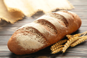 Fresh dark bread with spikelet of wheat on brown wooden table