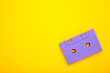 Old violet audio cassette on yellow background with copy space. Music day