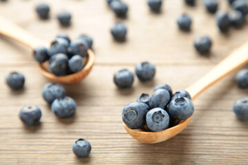 Fresh juicy blueberry fruits on a wooden spoons on grey background