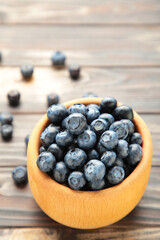Blueberries in a bowl on brown wooden table. Vertical foto