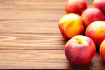 Many nectarines on brown wooden background with copy space