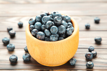 Blueberries in a bowl on brown wooden table.