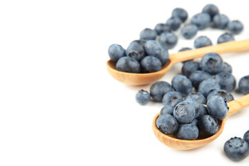 Fresh juicy blueberry fruits on a wooden spoons isolated on white background